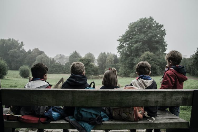 Children looking into a field. Photo by Piron Guillaume, Unsplash